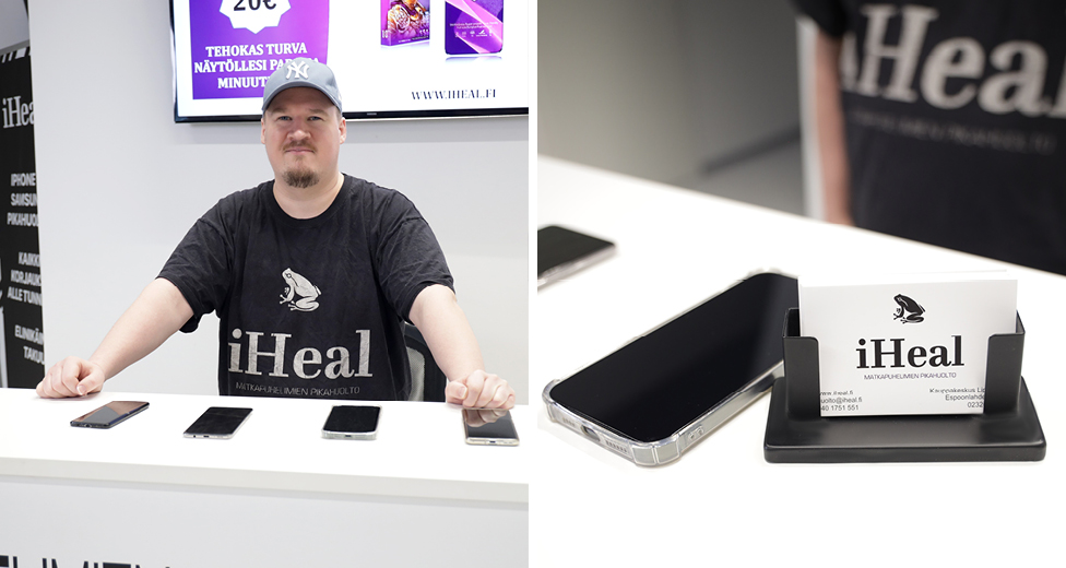 iHeal-yrittäjä seisomassa liikkeen tiskin takana. Tiskillä puhelimia sekä käyntikortteja.